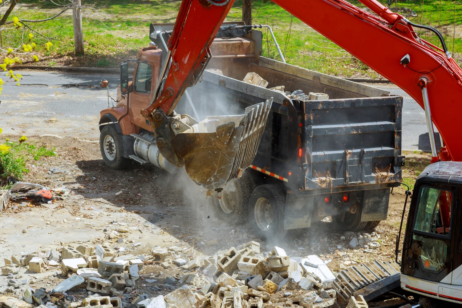 Excavator loading construction rubble into a dump truck